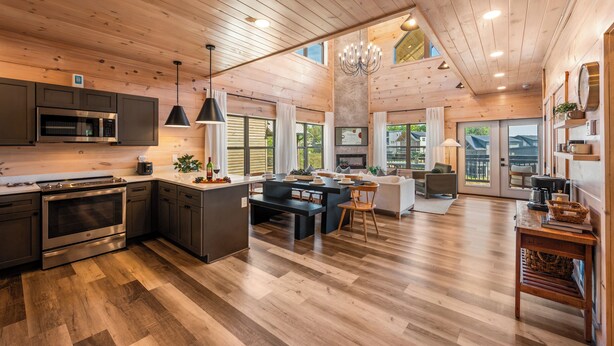 A spacious kitchen with a central island, built-in appliances, and a dining area with a sofa and chairs. - Modern Smoky Mountain Cabin Near Dollywood – Indoor Pool, Hot Tub & Arcade Fun (Pigeon Forge)