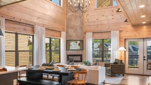A spacious living area with a fireplace, wooden ceiling, and large windows. - Modern Smoky Mountain Cabin Near Dollywood – Indoor Pool, Hot Tub & Arcade Fun (Pigeon Forge)
