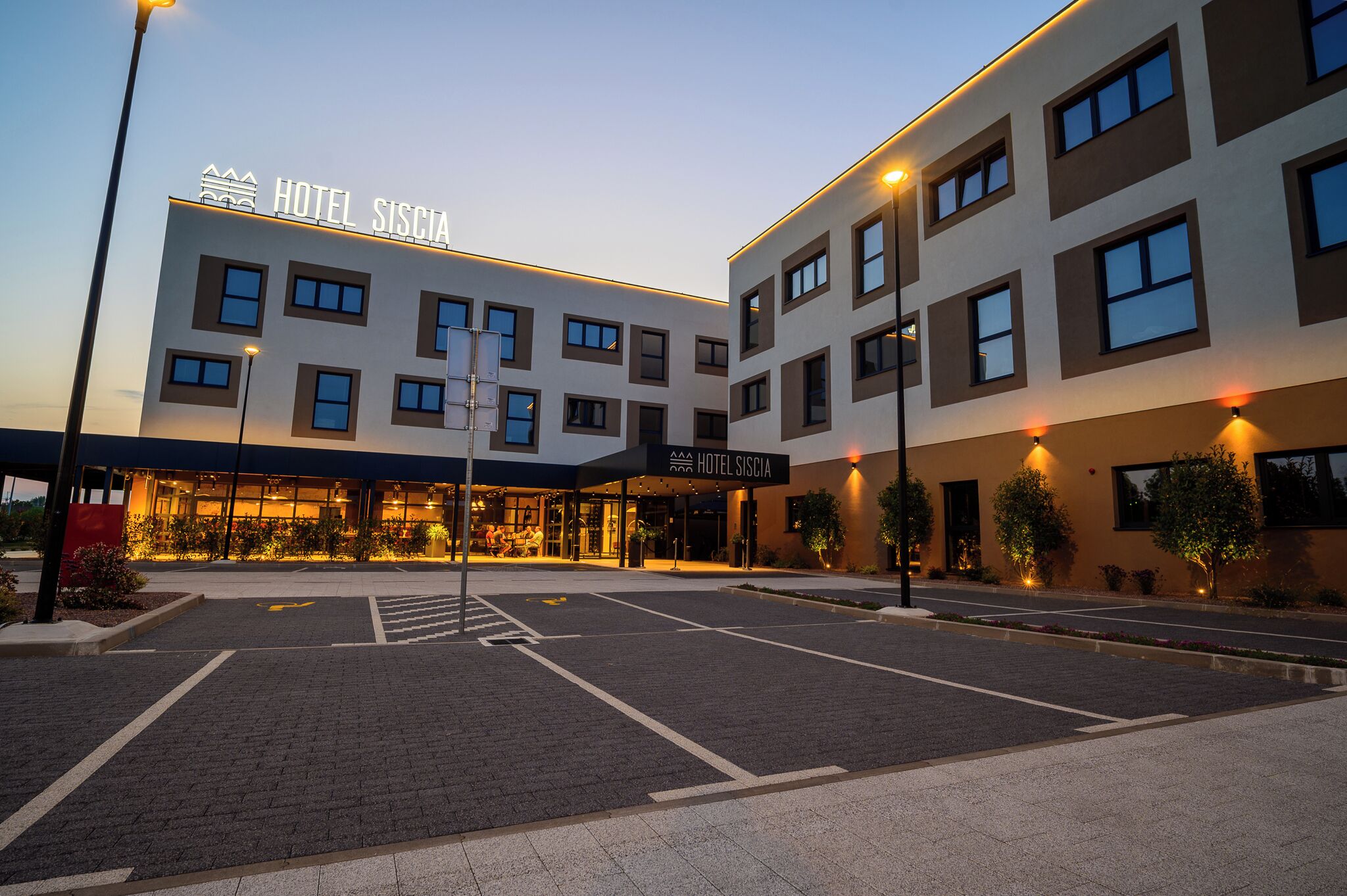 A modern hotel with a flat facade, multiple windows, and a well-lit entrance.