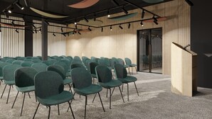 A conference room with rows of green chairs, a podium, and a wooden panel wall. - Hotel Siscia (Sisak)