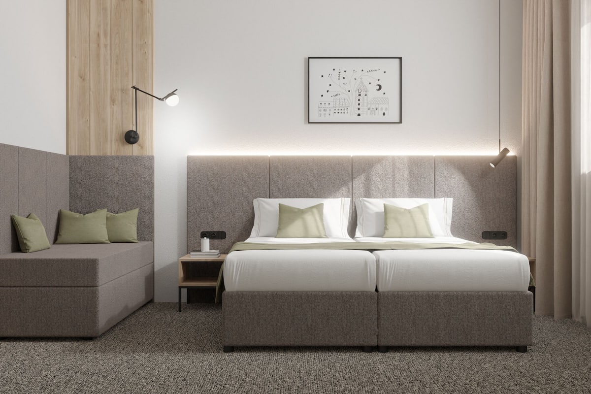 Une chambre d’hôtel moderne avec un grand lit, un canapé, une table de chevet et un tableau encadré au mur.