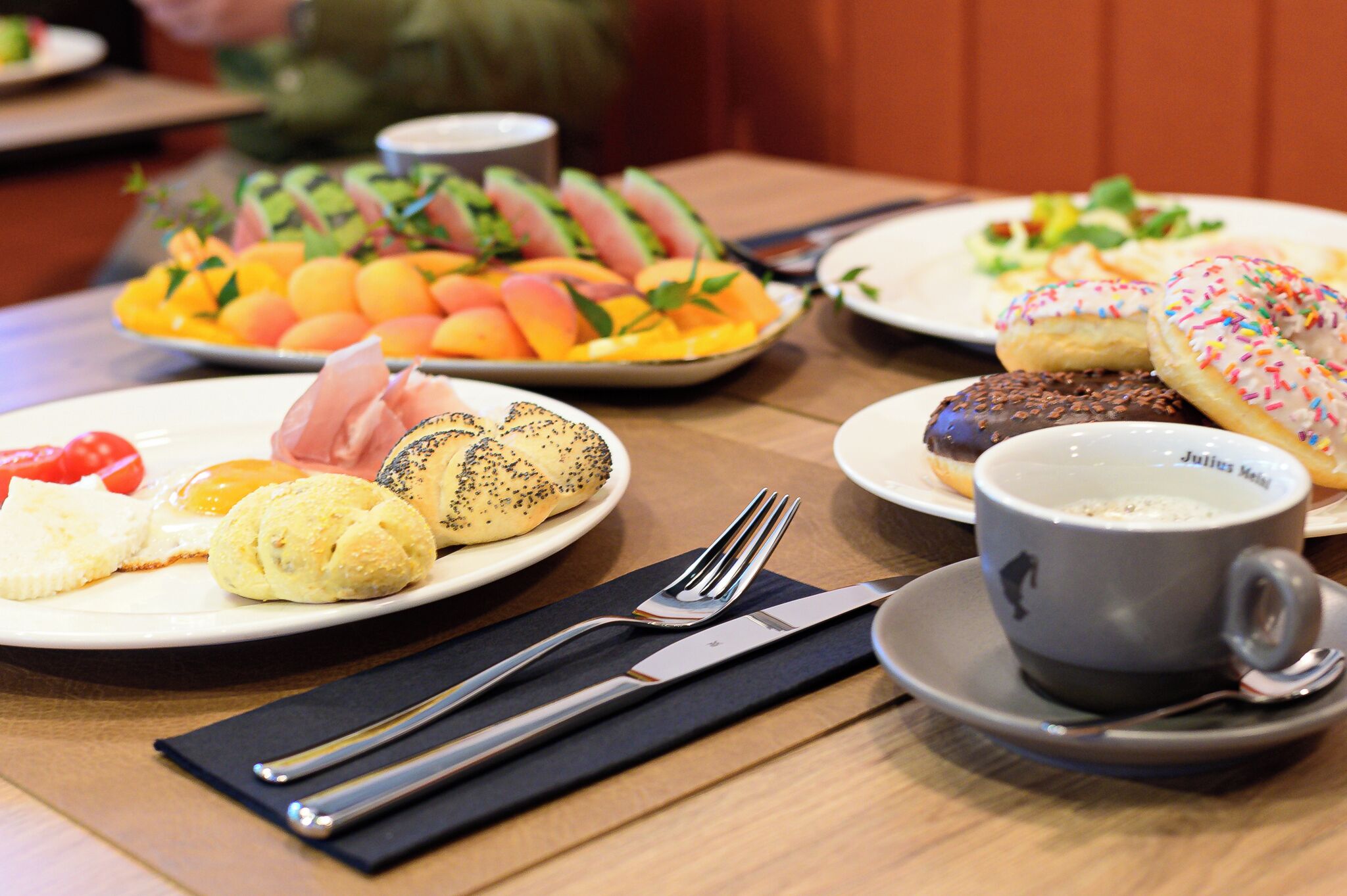 A table with plates of food, a cup, and cutlery.