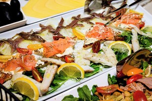 A variety of dishes including fish, vegetables, and bread, suggesting a buffet-style meal.