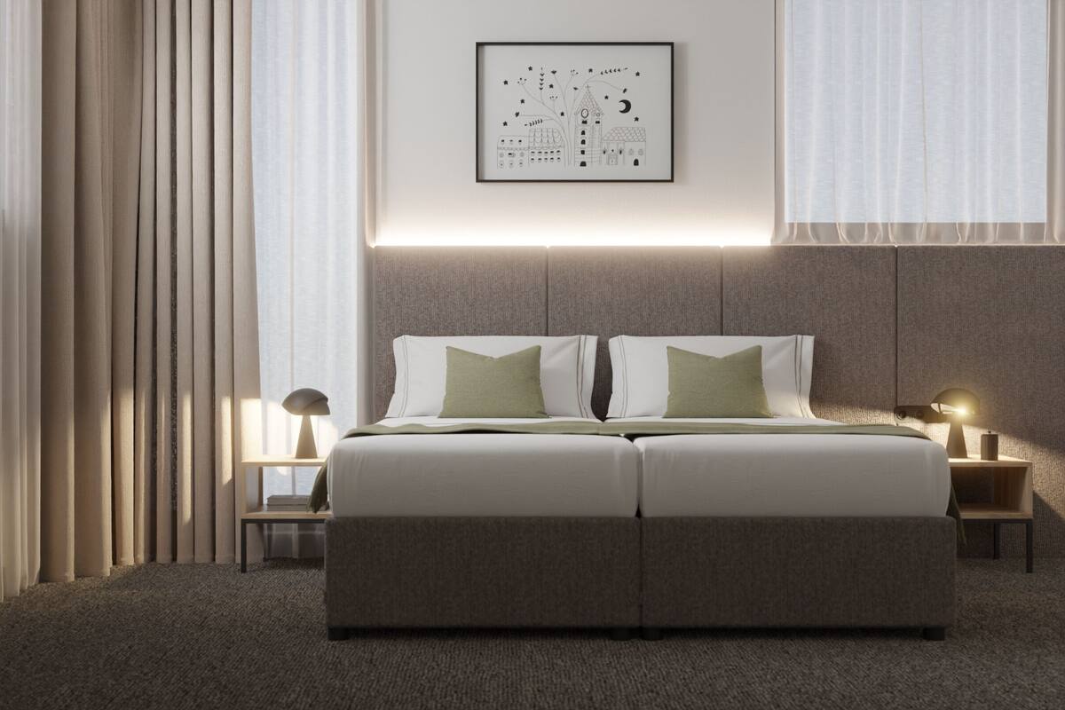 Une chambre d’hôtel moderne avec un grand lit, deux tables de chevet avec des lampes, une œuvre d’art encadrée au mur et une vue sur le paysage urbain par la fenêtre.