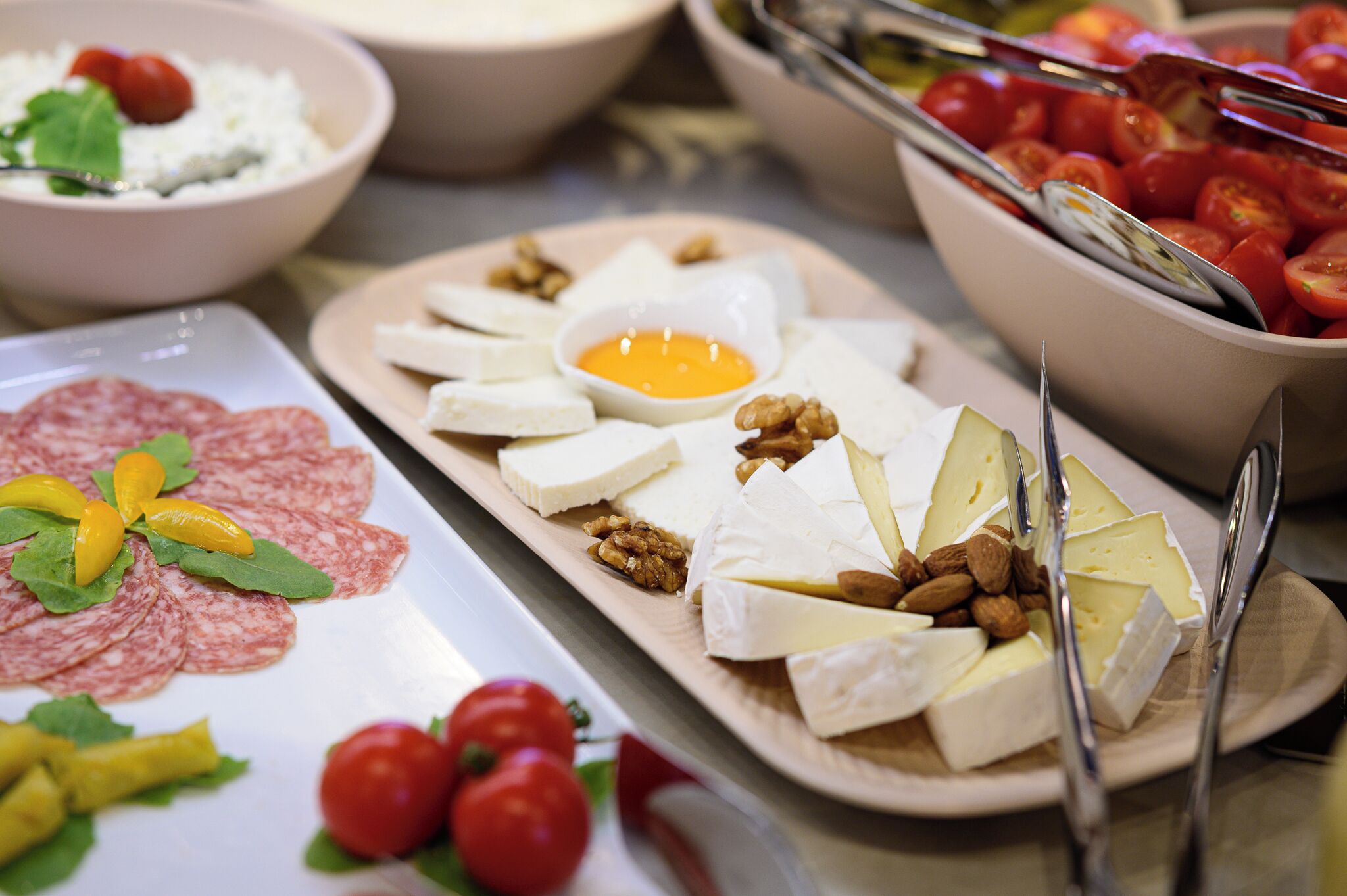 A variety of food items including cheese, nuts, and tomatoes on a buffet table.