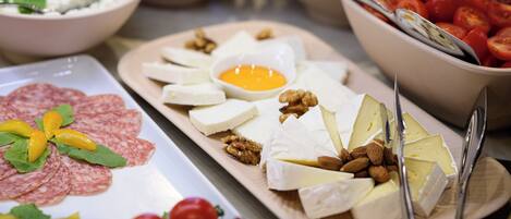 A variety of food items including cheese, nuts, and tomatoes on a buffet table.