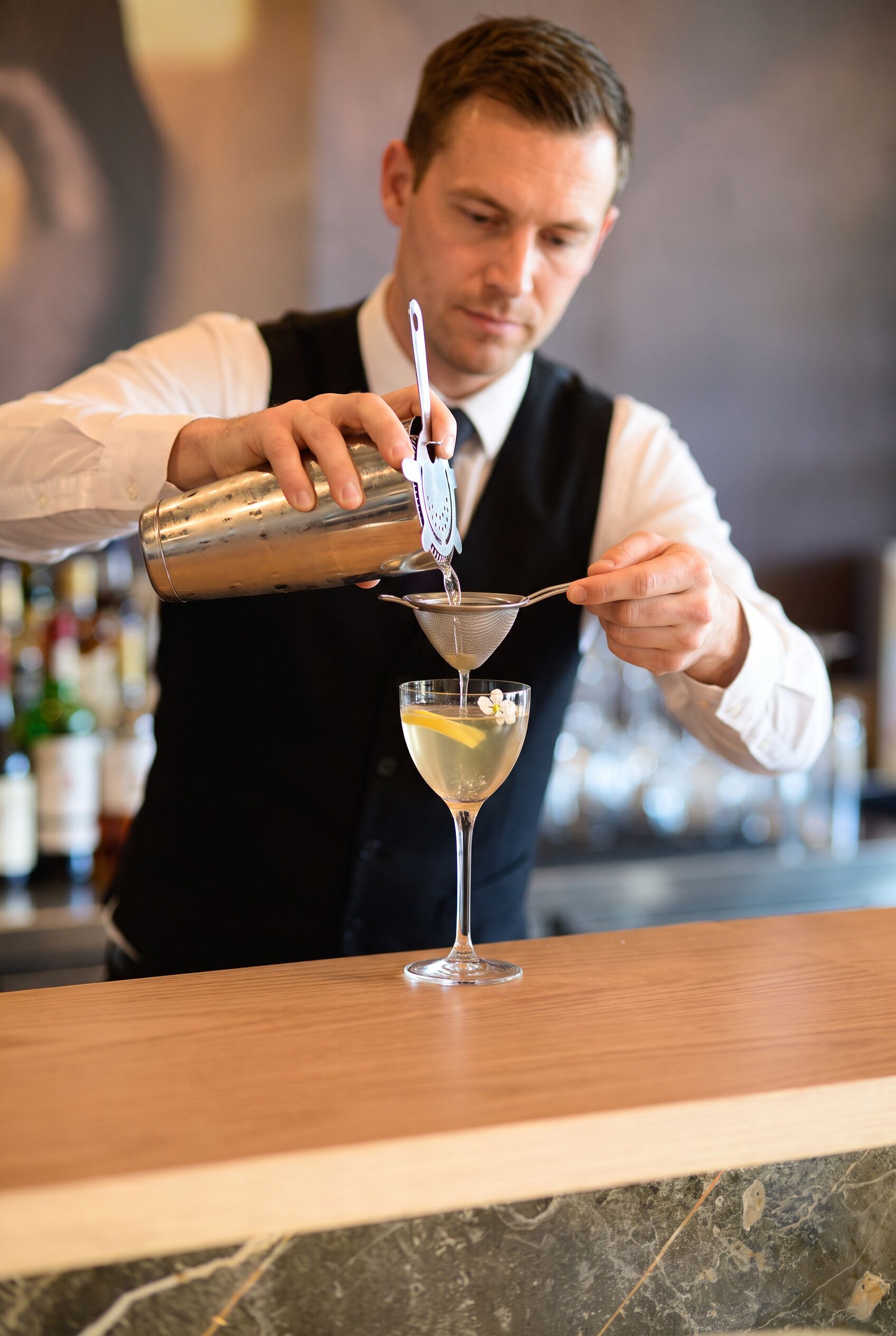 Un barman sirviendo una bebida en una copa de martini.