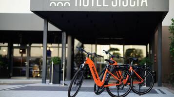 Een hotelentree met een bord waarop 'HOTEL SISCIA' staat en drie fietsen ervoor geparkeerd.