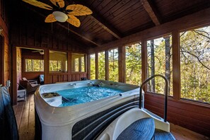 A hot tub with a wooden deck, large windows, and a ceiling fan. - Star Wars Smoky Mountain Cabin! Hot tub, Fire pit, Arcade, Private location! (Sevierville)