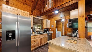 Una cocina con armarios de madera, electrodomésticos de acero inoxidable, encimeras de granito y un televisor integrado.