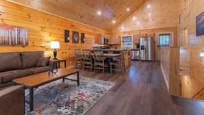 A spacious living area with a wooden ceiling, a sofa, a coffee table, and a dining table with chairs.