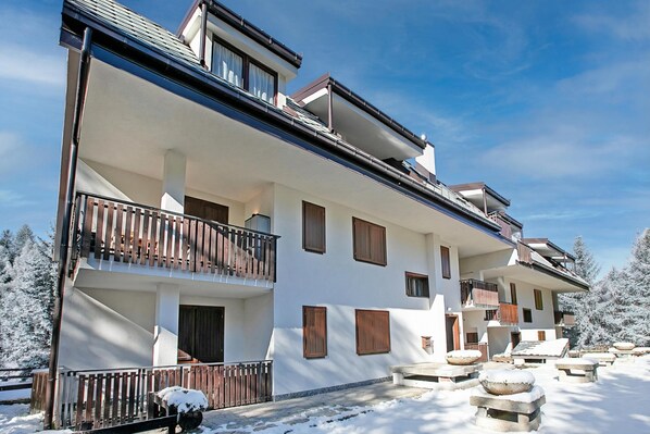 A multi-story building with balconies, wooden shutters, and a snow-covered landscape. - Appartamento Chez Mavi Cond Il (Sauze d'Oulx)
