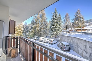 Ein Balkon mit Blick auf schneebedeckte Bäume und parkende Autos.
