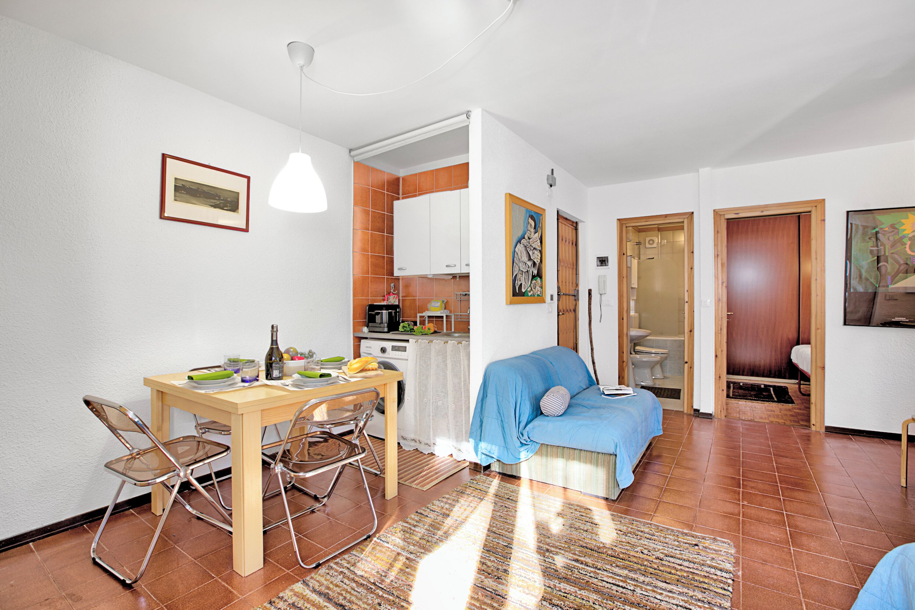 Un espace de vie compact comprenant un coin repas, une kitchenette et une chambre.