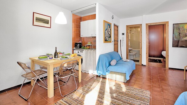 A compact living space with a dining area, kitchenette, and a bedroom.