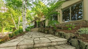 A stone staircase leading to a house with a stone foundation and large windows. - Luxury 4BR Stay with Swim Spa, Golf & Fireplaces (Caledon)