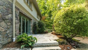A stone house with a stone staircase leading to a front door, surrounded by lush greenery and a stone pathway. - Luxury 4BR Stay with Swim Spa, Golf & Fireplaces (Caledon)