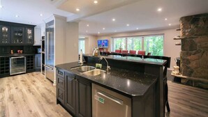 A modern kitchen with a large island, built-in appliances, and a stone accent wall. - Luxury 4BR Stay with Swim Spa, Golf & Fireplaces (Caledon)