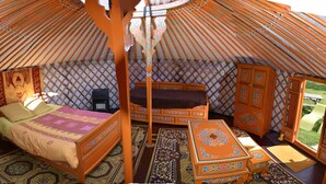 Et traditionelt yurt-interiør med seng, siddeområde og opbevaring.