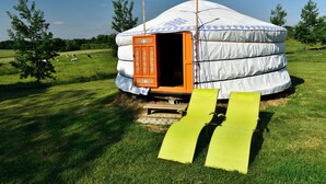 En yurt med åben dør, en træplatform og to gule stofsteg, der fører op til indgangen.