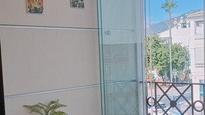 Uma varanda com mesa de vidro, um vaso de planta e uma cadeira.