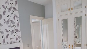 Quarto com cama, mesa de cabeceira, penteadeira e guarda-roupa.