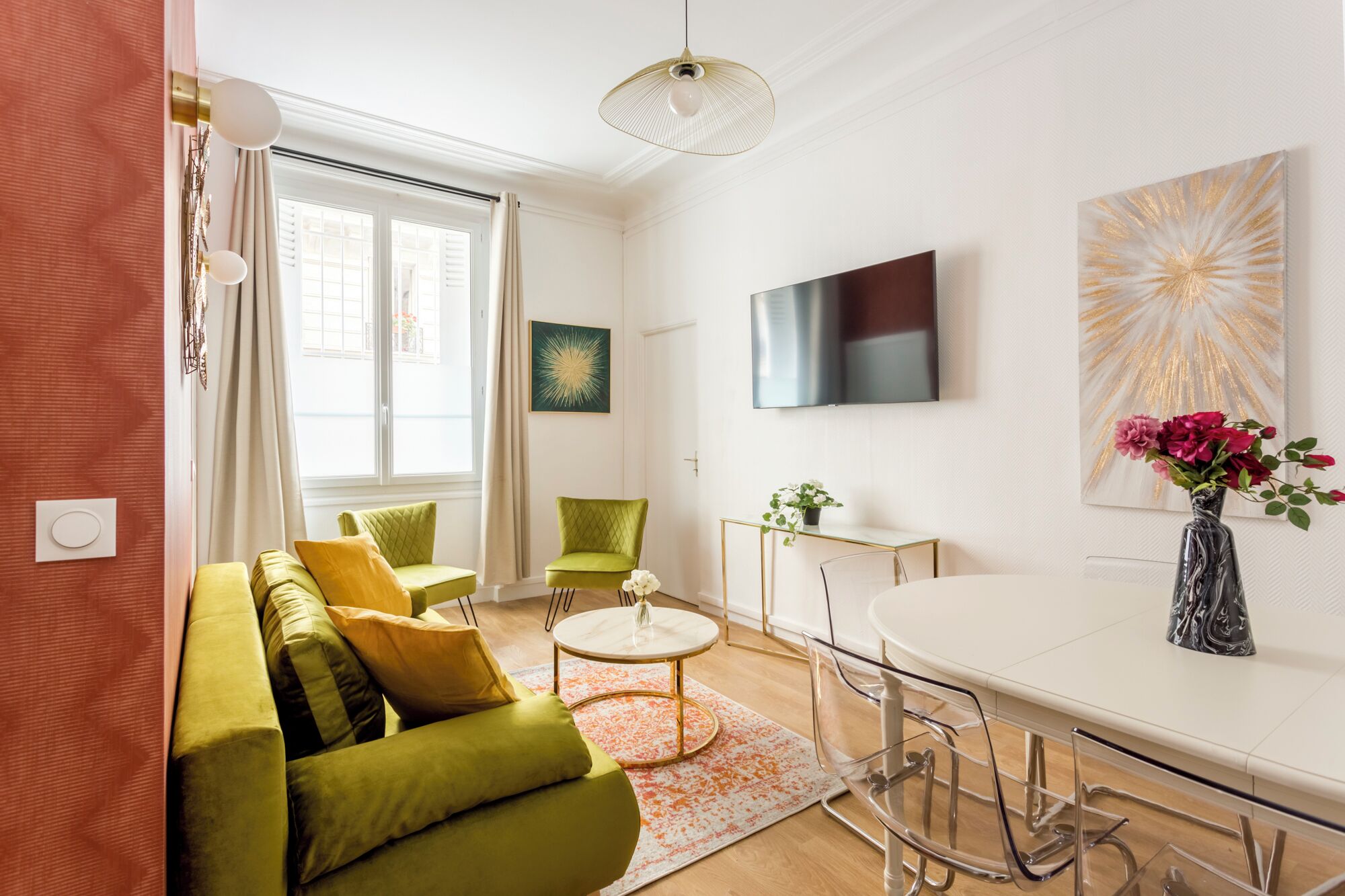 A modern living room with a green sofa, a coffee table, and a TV mounted on the wall.