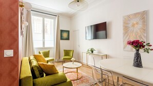 Un soggiorno moderno con un divano verde, un tavolino da caffè e una TV a parete.