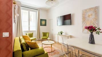 A modern living room with a green sofa, a coffee table, and a TV mounted on the wall.