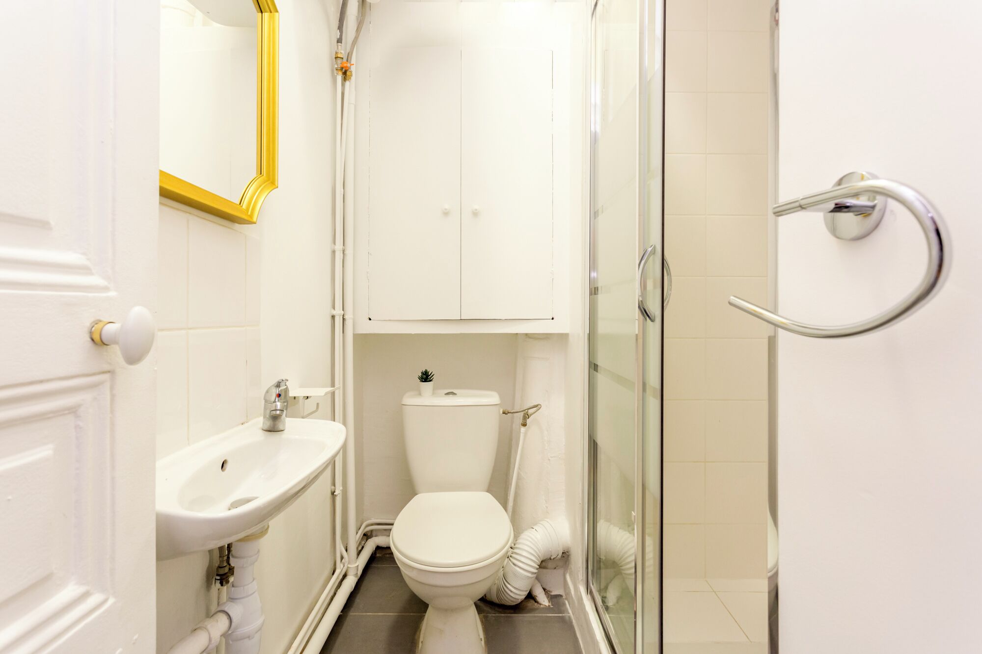 A small, compact bathroom with a white sink, toilet, and shower.