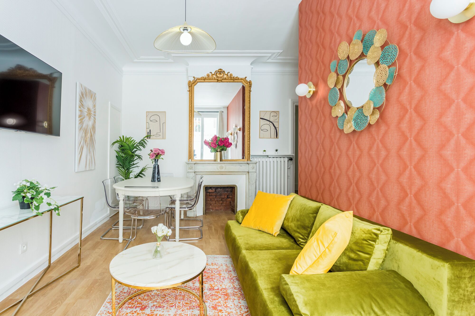 A living room with a green sofa, a round coffee table, a fireplace, and a large mirror.