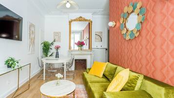 A living room with a green sofa, a round coffee table, a fireplace, and a large mirror.