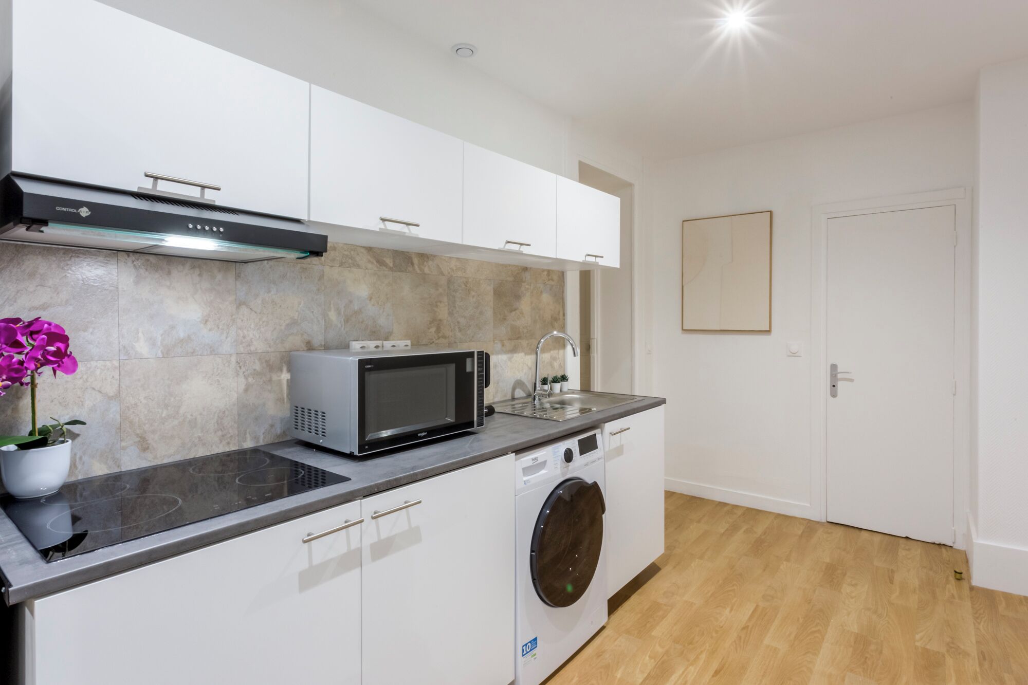 A compact kitchen with a microwave, toaster, and washing machine.