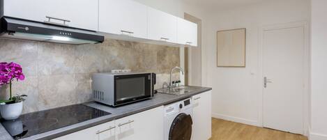 A compact kitchen with a microwave, toaster, and washing machine.