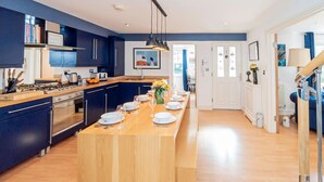 Une cuisine moderne avec des meubles de couleur bleu foncé, un îlot central en bois et un coin repas.