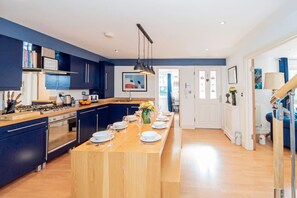 Een moderne keuken met donkerblauwe kastjes, een houten eiland en een zithoek.