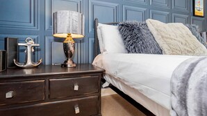 Une chambre à coucher comprenant un lit, une table de chevet, une lampe et un objet décoratif en forme d’ancre.