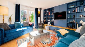 Un salon moderne avec un canapé bleu, un téléviseur et une bibliothèque.