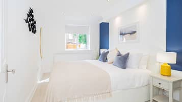 A bedroom with a bed, bedside tables, a window, and a view of the outdoors.
