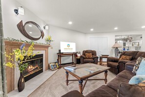 A living room with a fireplace, a sofa, a coffee table, and a television displaying 'GRAND WELCOME.' - Fairway Retreat for 6 – Walk-in and Pet Friendly (Branson)