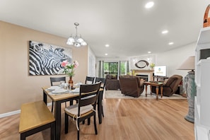 Uma sala de estar moderna com área de jantar, lareira e uma grande pintura de zebra na parede.