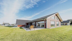 A modern house with a large patio, a dining area, and a garage. - Ferienhaus in Dagebuell im skandinavischen Stil (Dagebüll)