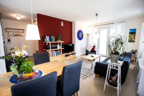 Un salon moderne avec une table à manger en bois, un canap é, un téléviseur et une bibliothèque.