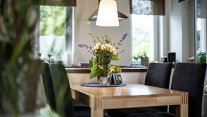 Une table à manger ornée d’un vase de fleurs, d’un calendrier et d’un set de table bleu.