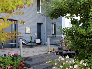 Un bâtiment bleu doté d’un porche, de sièges en plein air et d’un escalier menant à l’entrée.