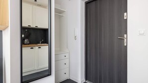 Ein modernes Interieur mit einer dunklen Holztür, weißen Schränken und einem eingebauten Spiegel.