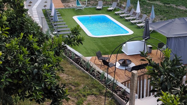 Un jardin avec une piscine, des chaises longues et un espace barbecue.