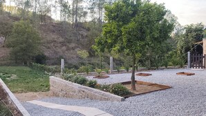 Un espace extérieur aménagé avec des allées de gravier, un arbre et un mur en pierre.