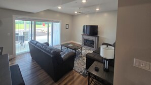 A modern living room with a sofa, a TV, a fireplace, and a dining area. -  Condo 5127 D Bellaire (Bellaire)
