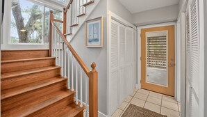 A wooden staircase with white railings leading to a room with a door and a window.